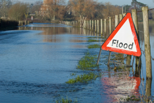 Flood sign in front of flooded road